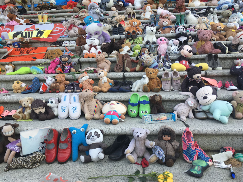 close up of legislative steps of Victoria BC parliament buildings covered in toys and shoes for the first nations children on truth and reconcillation day