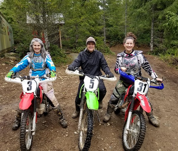 christina merkley, chanel monk and louisa on their dirt bikes in the forest of vancouver island