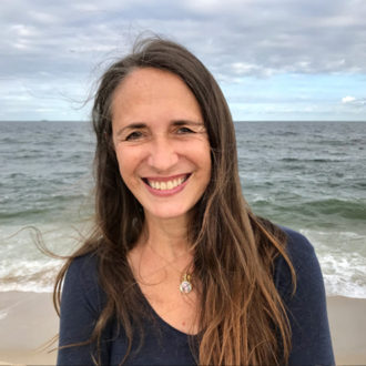 Anneke Lucas on the beach in front of the ocean on a cloudy day