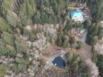arial drone shot of forest retreat center on vancouver island, british columbia. Complete with pond.
