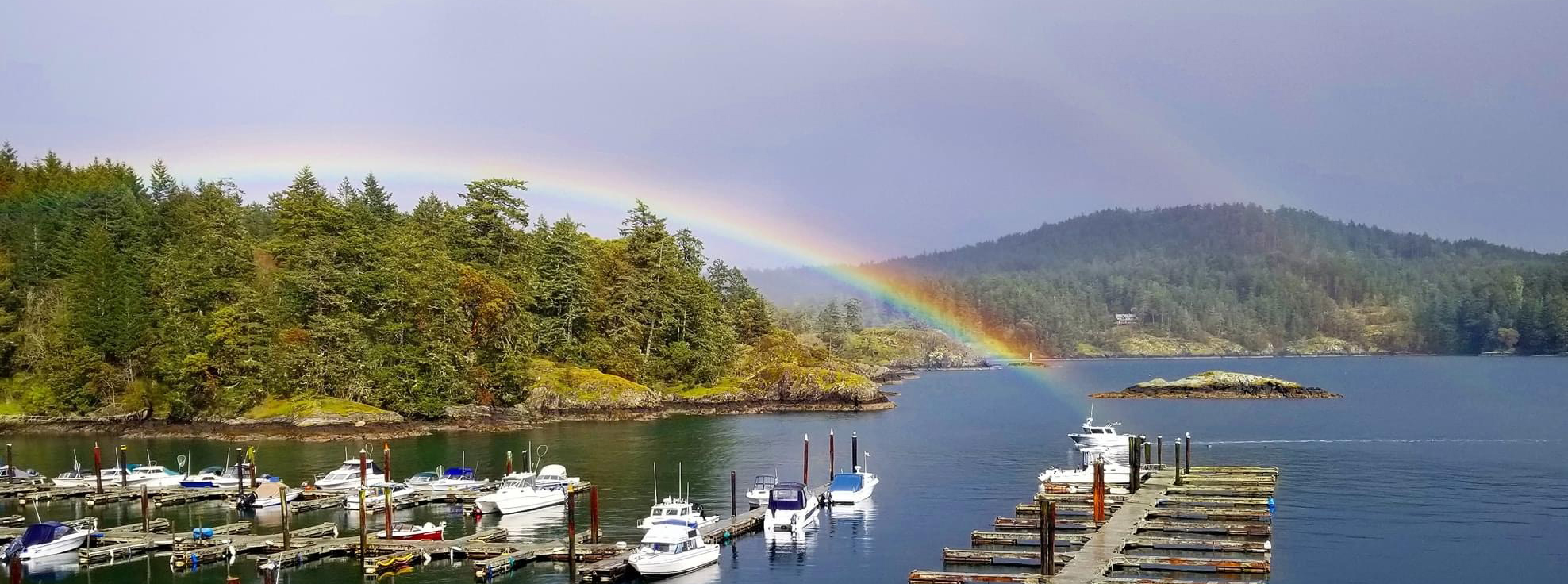 Victoria boat docks with beautiful rainbow just cresting the trees and ending in the water