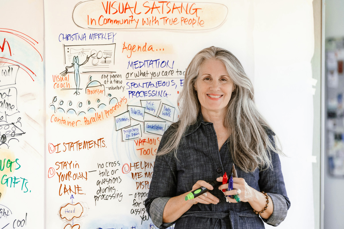 Christina Merkley standing in front of large visual map, markers in hand